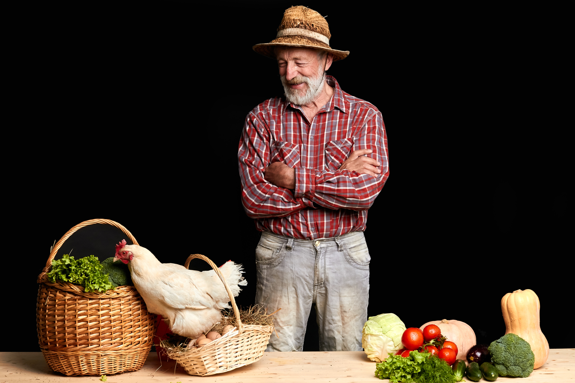 Mature farmer giggling and looking at hen jumping out of basket with fresh eggs